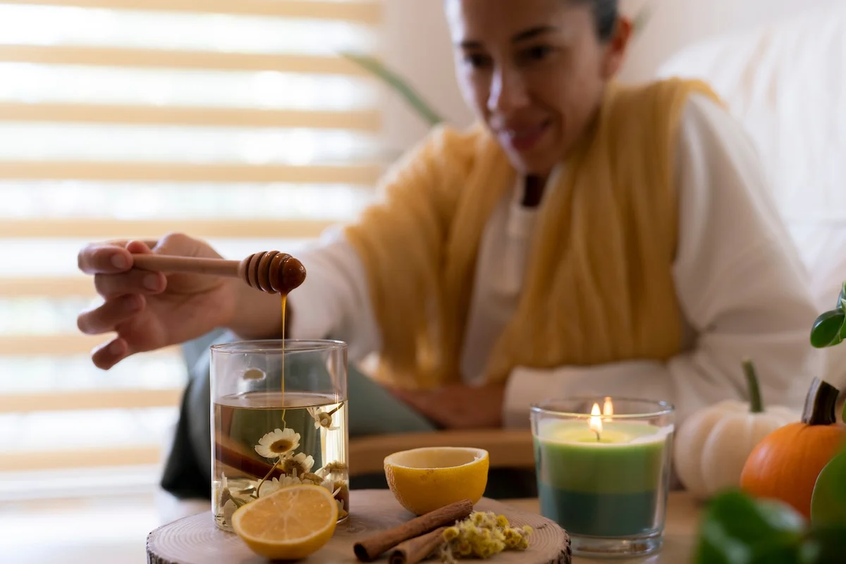 Person die ein Glas mit Tee mit Honig befüllt